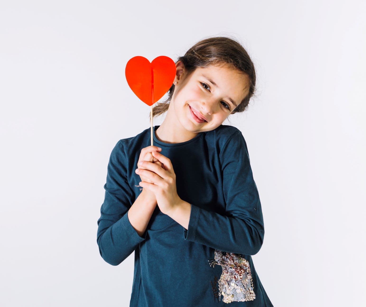 niña sujetando un corazón de cartulina en sus manos y sonriendo