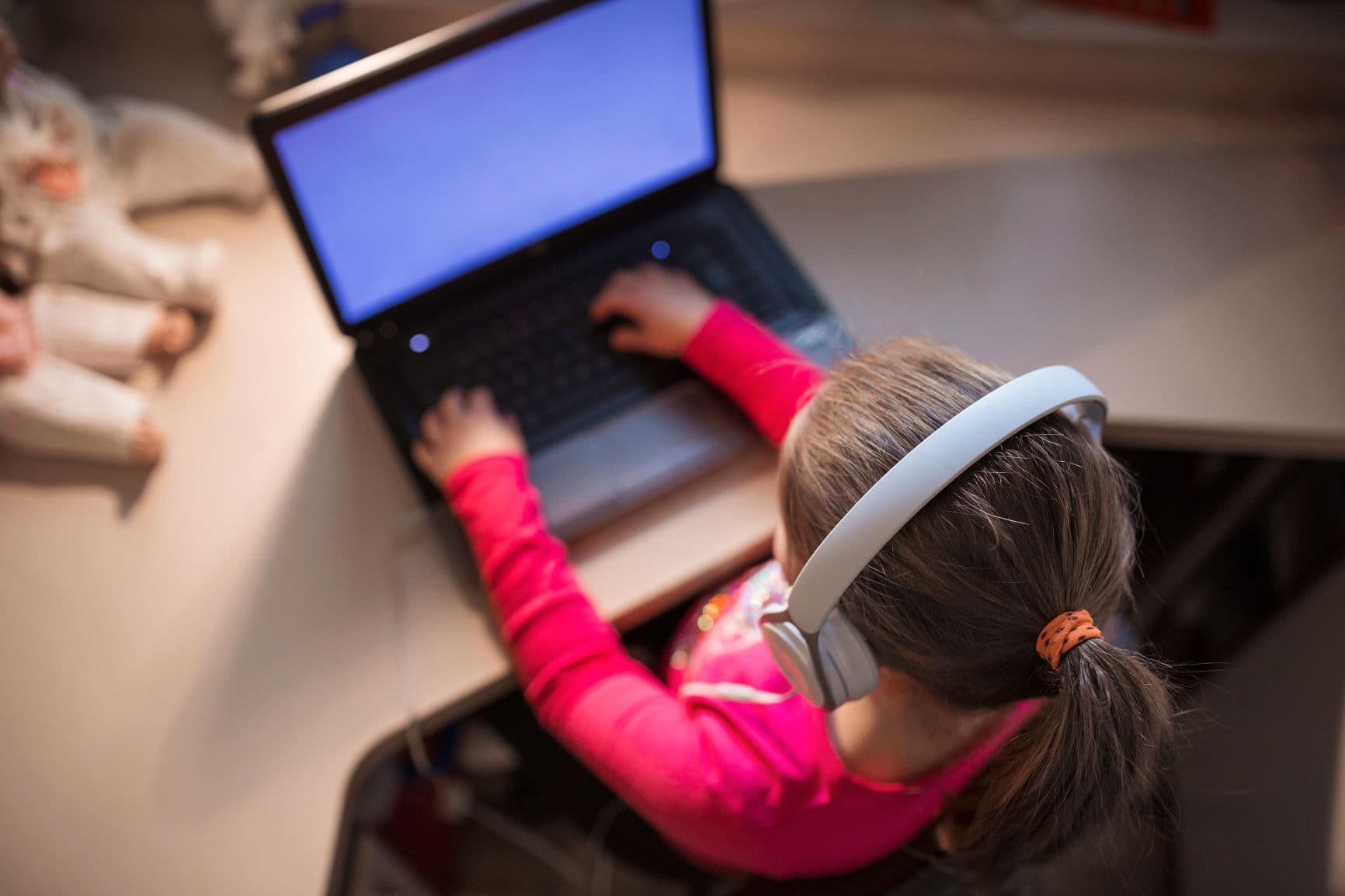 niña sentada frente a un computador usando audífonos