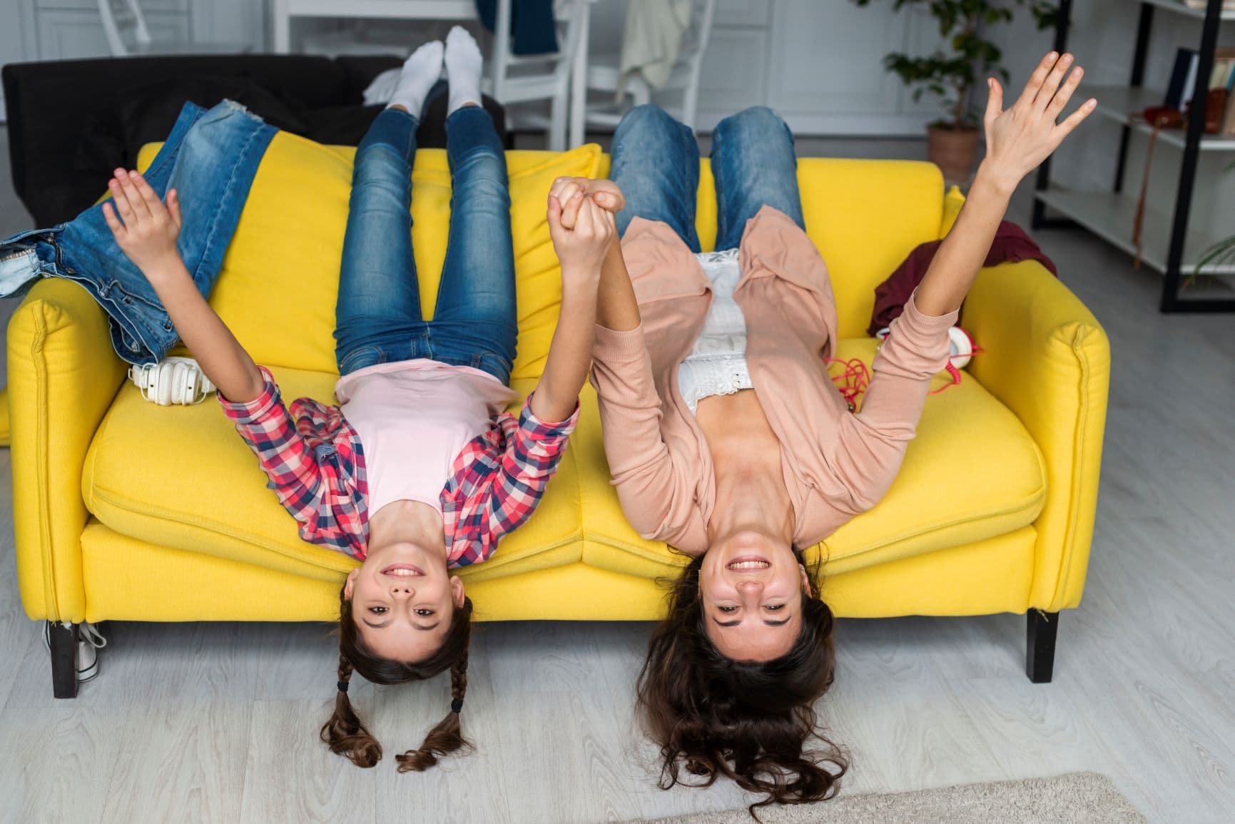 niña y mujer en un sillon con la cabeza hacia el suelo