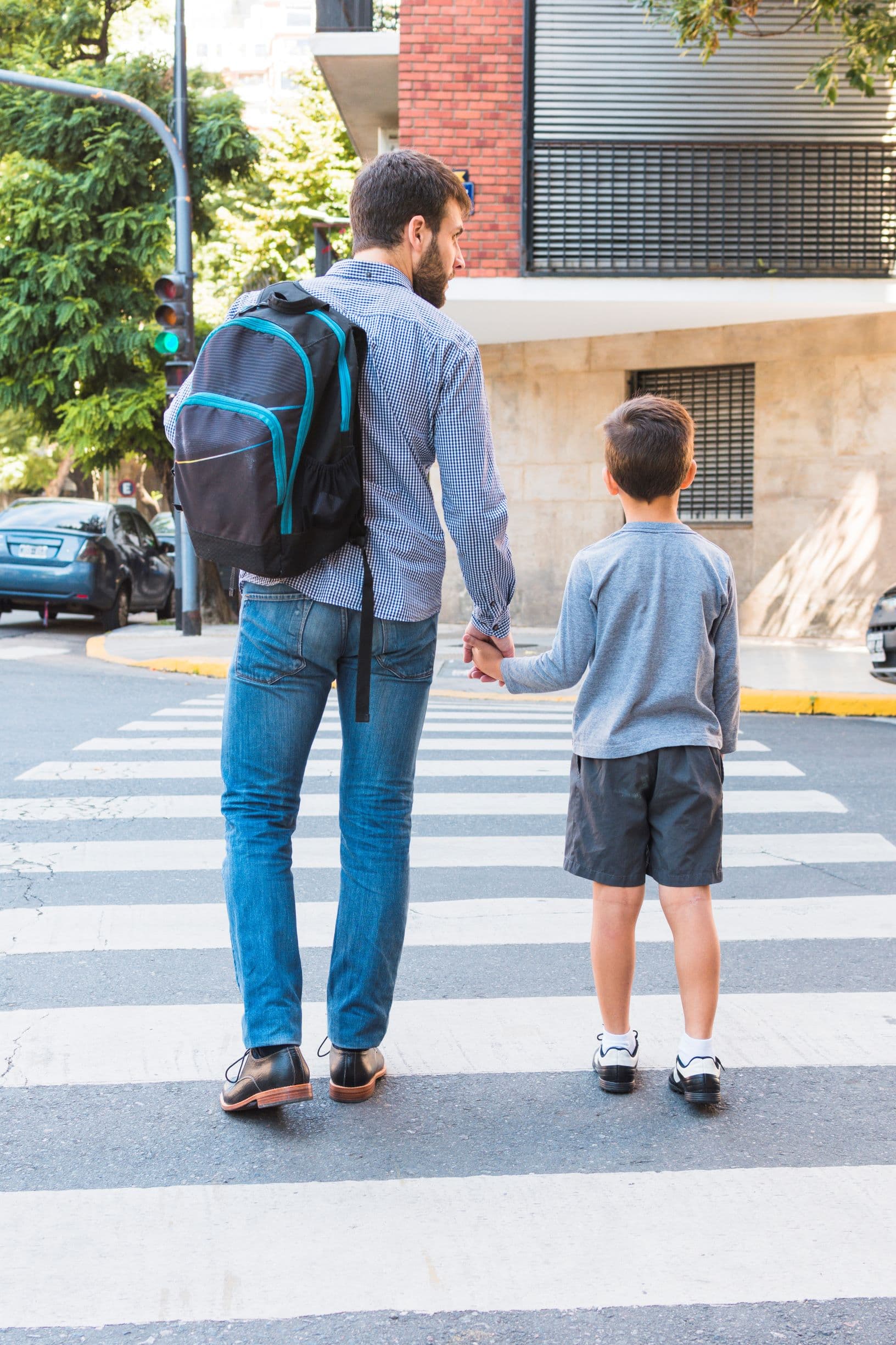 niño y papá de la mano cruzando la calle