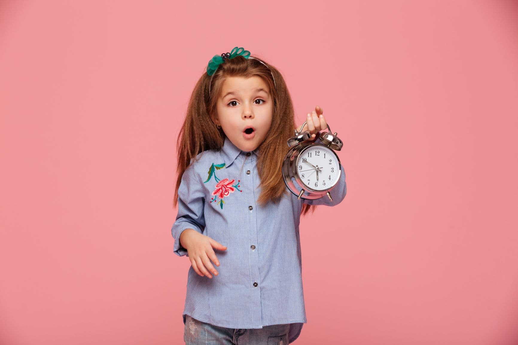 niña con cara de asombro con un reloj despertador en la mano